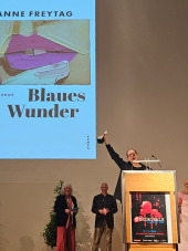 Anne Freytag streckt ihren gewonnen Glauser-Preis stolz in die Luft.